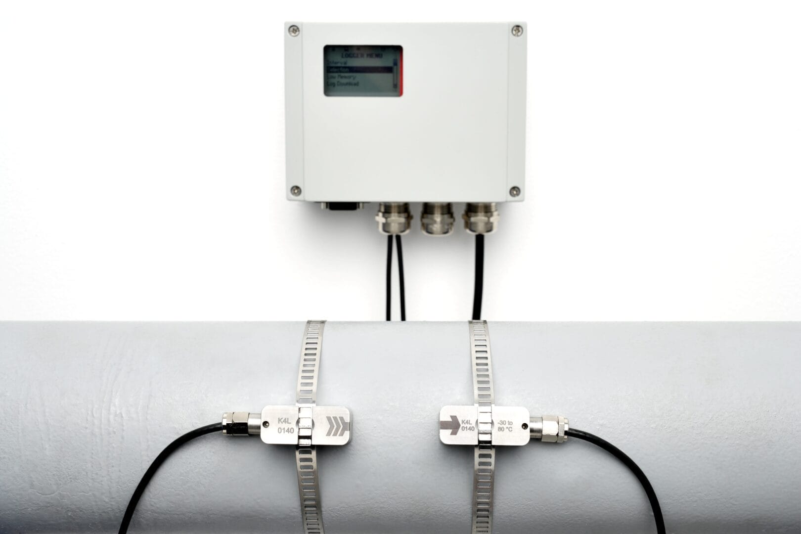 Fastmontert Katronic‑flowmeter med to clamp‑on sensorer festet på et stort rør og tilkoblet enheten via kabler.